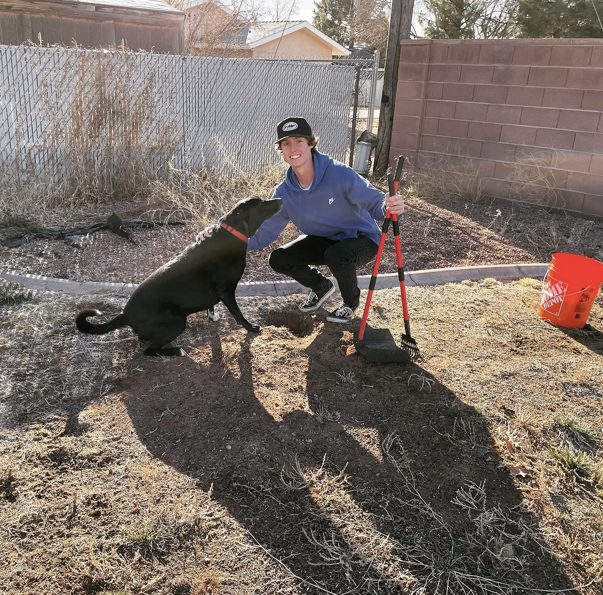 A friendly Arrowhead Pooper Scoopers team member petting a happy dog after scooping the yard